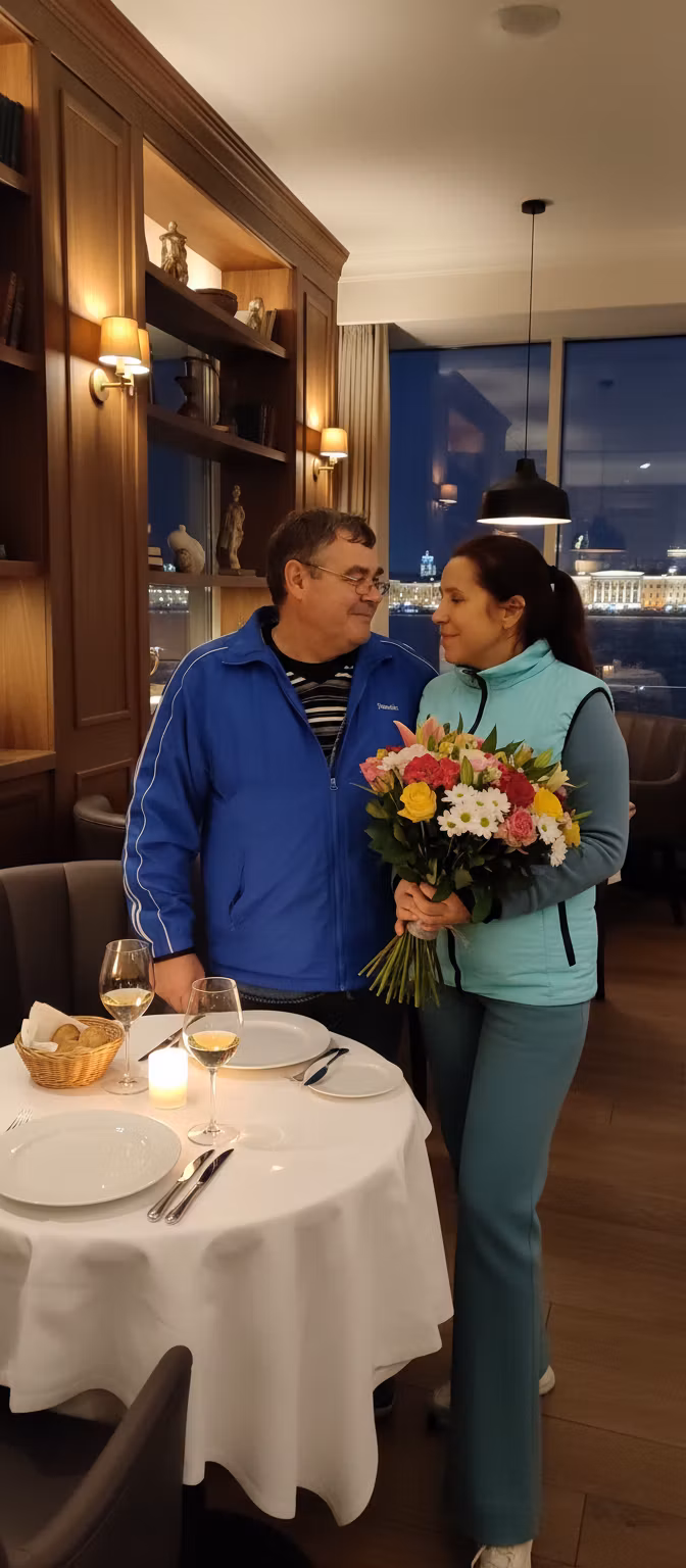 Лариса Примоченко – Romantic scene in an elegant restaurant: a middle-aged woman with a soft smile, holding a beautiful bouquet of colorf…