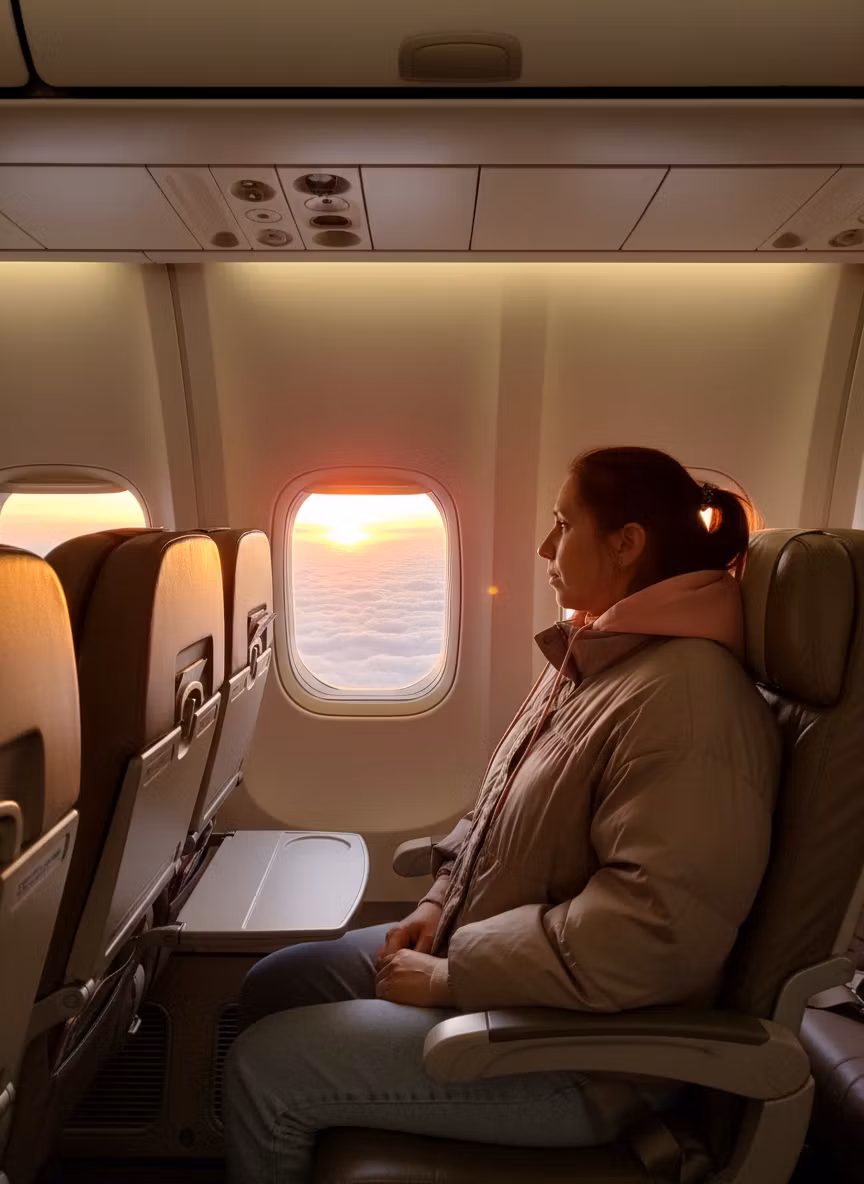 Лариса Примоченко – A realistic scene inside an airplane cabin during a flight. A young woman with brown hair tied back, wearing a light …