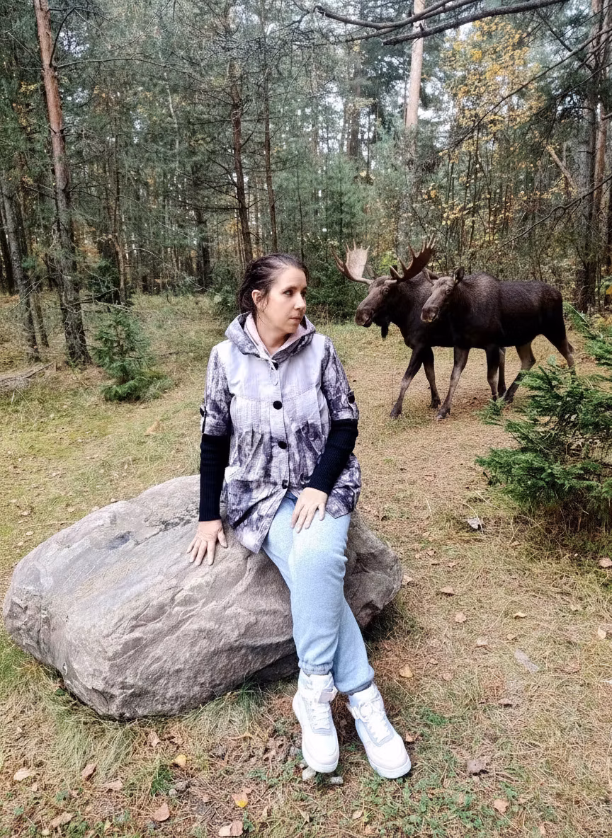 Лариса Примоченко – In the forest clearing scene with the young woman sitting on a rock, add two or three majestic moose walking calmly n…