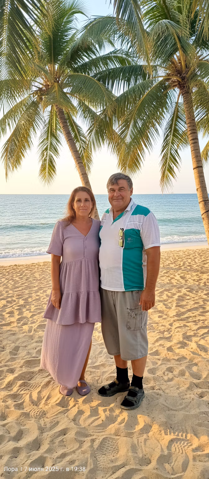 Лариса Примоченко – A romantic couple standing together on a pristine tropical beach under swaying palm trees. The woman wears a flowing …