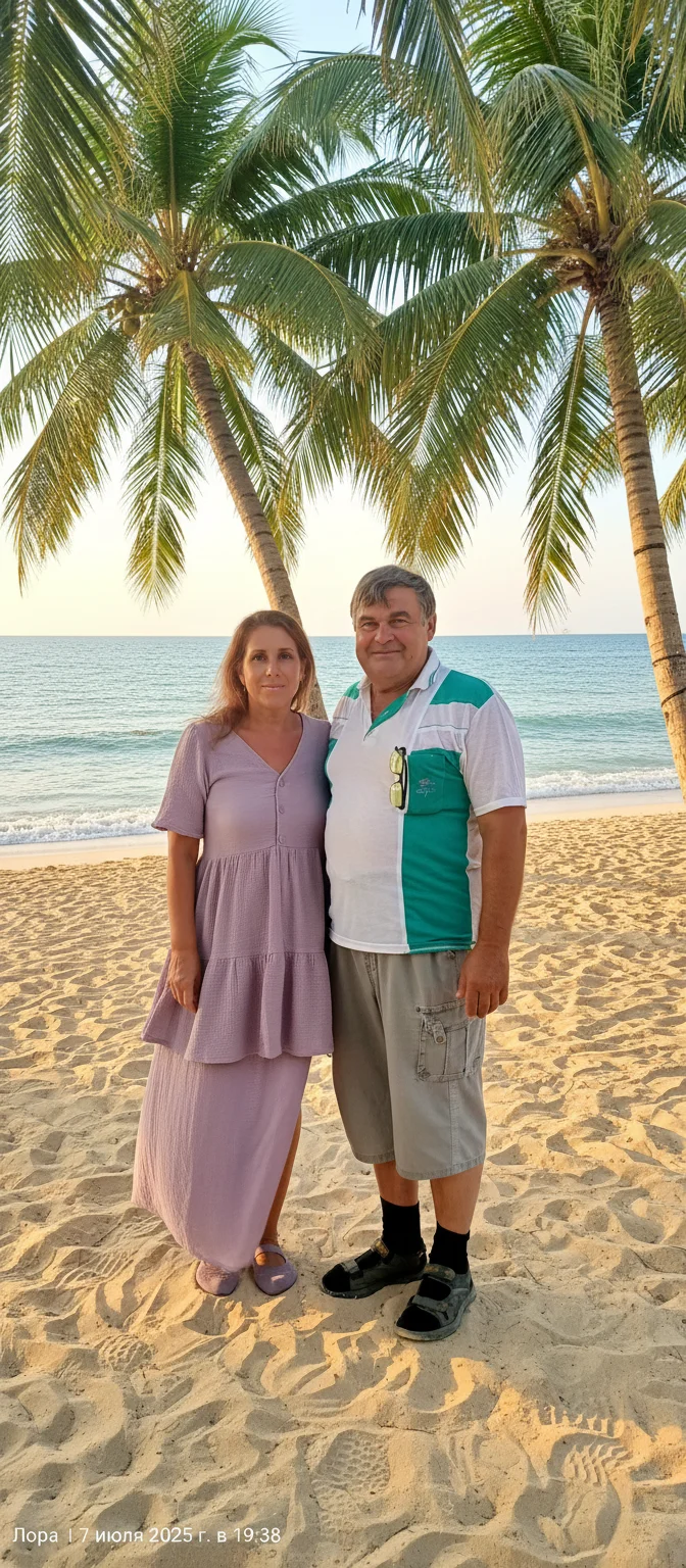 Лариса Примоченко – A romantic couple standing together on a pristine tropical beach under swaying palm trees. The woman wears a flowing …