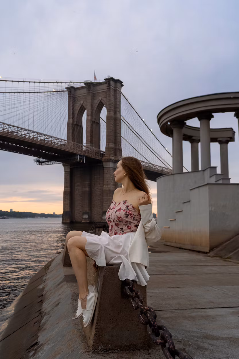 Павел Кочев – Using the provided image of a woman in white dress by the water at sunset, add a magnificent detailed suspension brid…
