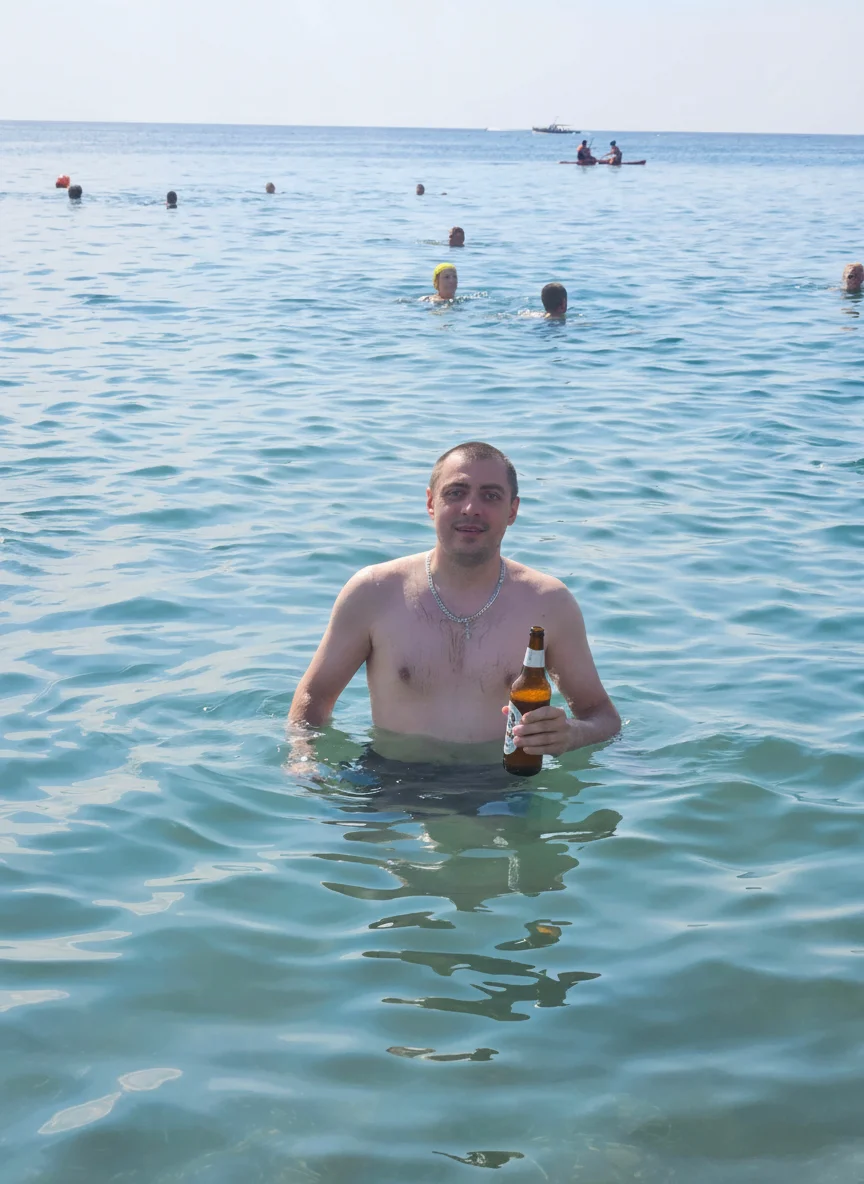 Михаил Сысоев – Using the provided image of the man standing in shallow seawater, add a cold beer bottle in his right hand. The man s…